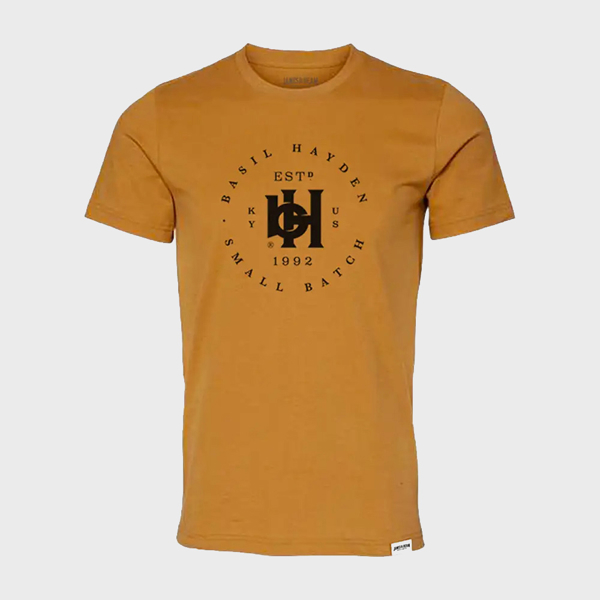 Front of the orange shirt. In the center, printed in black, there is the Basil Hayden symbol, with “Basil Hayden” written in a circular fashion around the symbol. The bottom-half of the circle is written “Small Batch”.