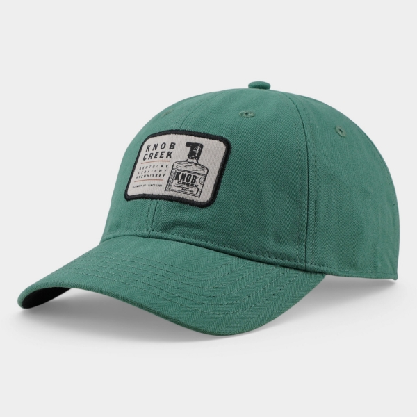 Angled front view of the Knob Creek Green Patch Cap featuring green herringbone fabric, a curved brim, and bottle logo patch